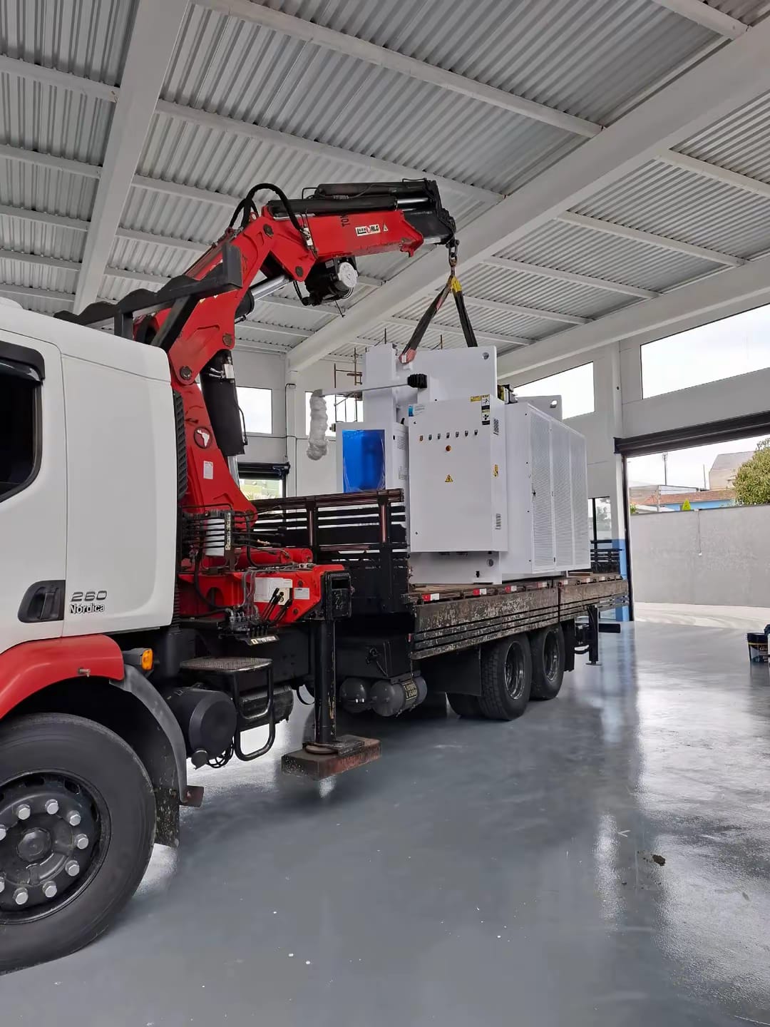 Guindauto Luna ALG do caminhão munck movimentando máquina industrial dentro de galpão em Curitiba